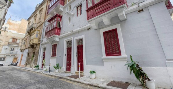 A row of white buildings with red shutters and balconies.