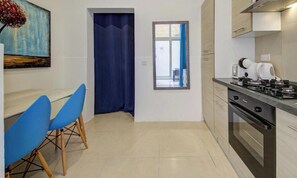 A compact kitchen with a stove, oven, and a dining area with blue chairs.