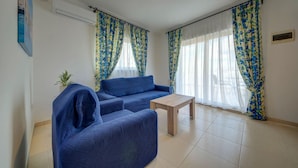A living room with a blue sofa, a small wooden table, and floral curtains.