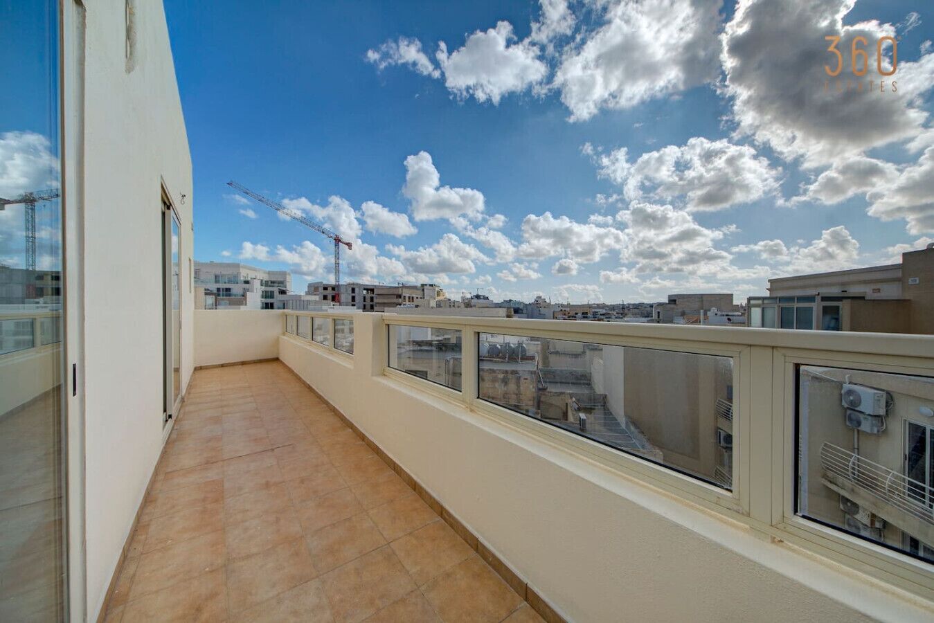 Ein Balkon mit Blick auf die Stadtlandschaft und im Hintergrund Baukräne.