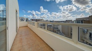A balcony with a view of the cityscape and construction cranes in the distance.