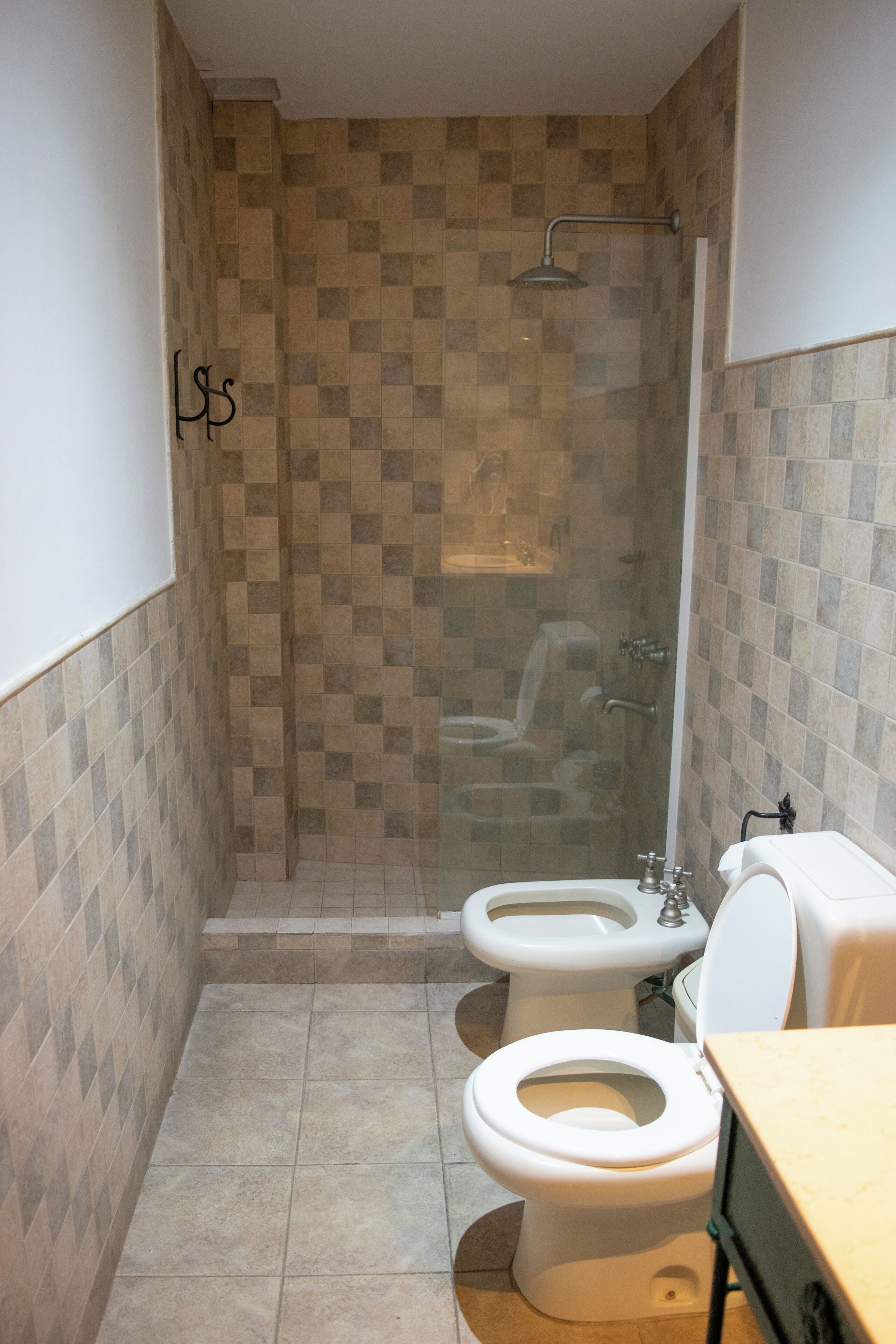 A bathroom with two toilets, a shower, and a sink.