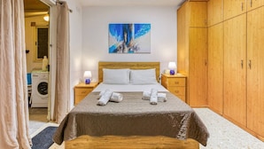 A bedroom with a bed, a washing machine, and a wardrobe. - Lovely 1BR Apt with full amenities in Bugibba! (San Pawl il-Baħar)