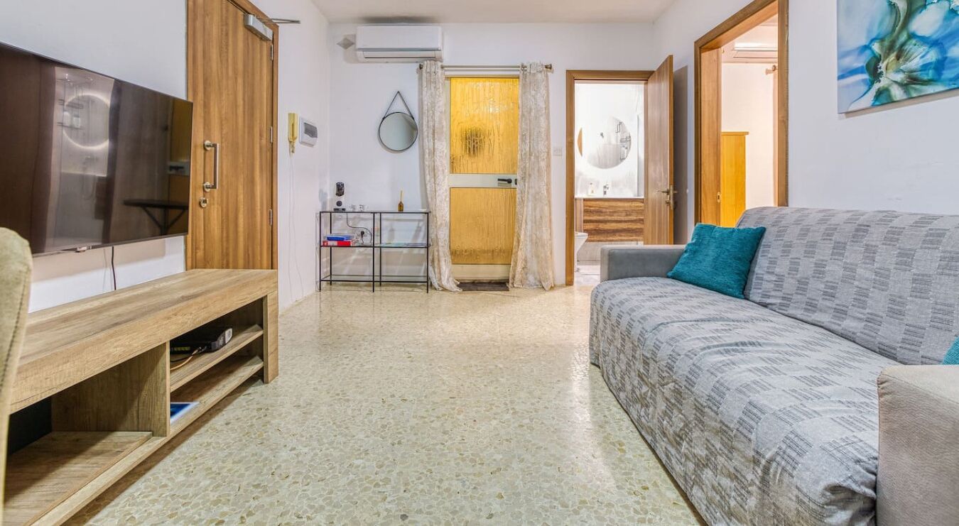Ein Wohnzimmer mit einer Couch, einem Fernseher, einem Holzschrank und einer Vitrine.