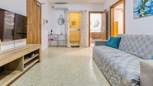 A living room with a sofa, a TV, a wooden cabinet, and a glass cabinet. - Lovely 1BR Apt with full amenities in Bugibba! (San Pawl il-Baħar)