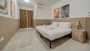 A hotel room with a bed, a bedside table, a lamp, and artwork on the walls. - A beautiful 4BR heaven close to the beach w/WIFI (Wied il-Għajn)