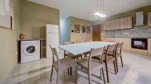 A compact kitchen with a built-in washing machine, a dining table with chairs, and light-colored cabinets. - A beautiful 4BR heaven close to the beach w/WIFI (Wied il-Għajn)