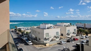A coastal residential area with modern buildings, a parking lot, and a view of the ocean. - A beautiful 4BR heaven close to the beach w/WIFI (Wied il-Għajn)