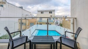A rooftop pool area with a table and chairs, surrounded by buildings.