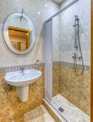 Un baño con lavamanos, espejo y ducha.