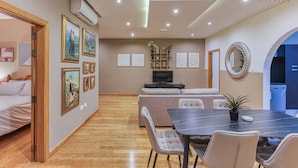 A modern living room with a dining area, a sofa, a TV, and artwork on the walls. - Lovely spacious 3BR Apt in the heart of St`Julians (San Ġiljan)