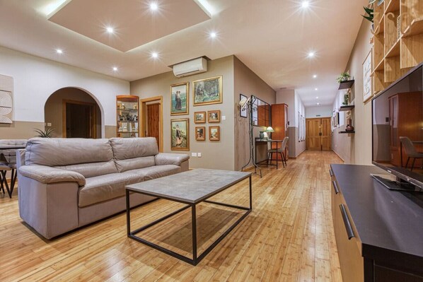 Un salón amplio con un sofá de cuero, una mesa de centro y una zona de comedor con mesa y sillas.