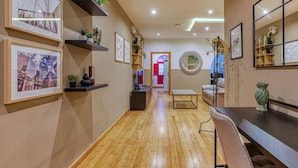 A hallway with wooden flooring, framed pictures on the walls, and a dining area with a table and chairs. - Lovely spacious 3BR Apt in the heart of St`Julians (San Ġiljan)