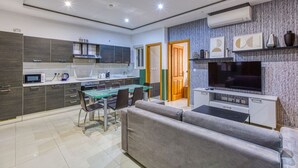 A modern kitchen with a dining area, a sofa, and a TV.