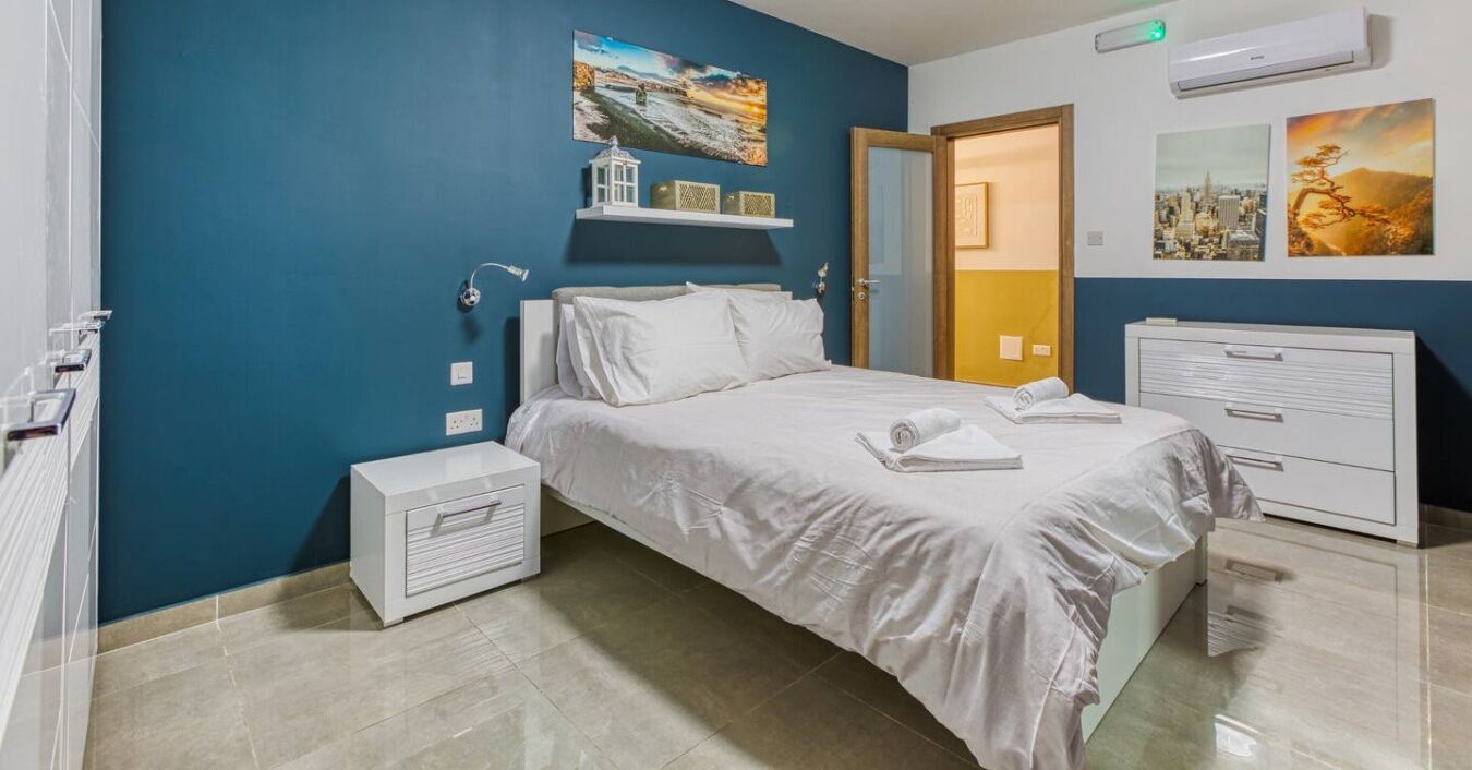 A neatly arranged bedroom with a bed, bedside tables, and a wardrobe.