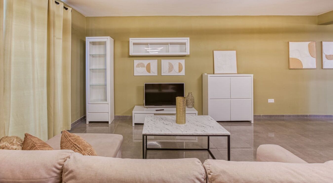 A living room with a sofa, a coffee table, a TV, and a cabinet.