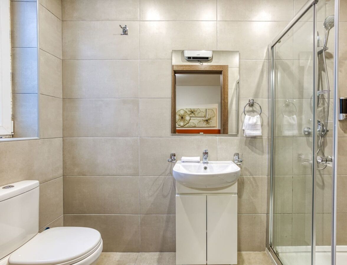 A modern bathroom with a toilet, sink, and glass shower enclosure.