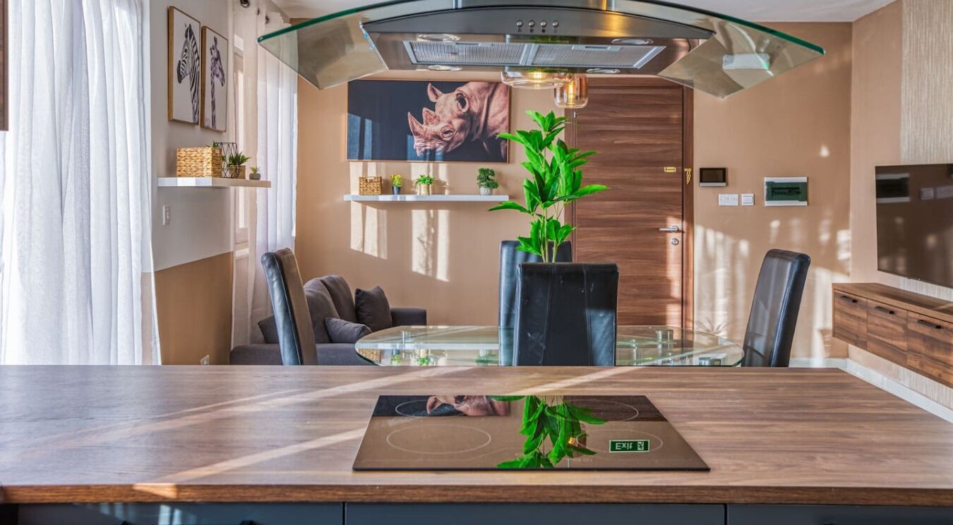 Una cocina moderna con mesa de vidrio, estufa integrada y un amplio ventanal.