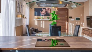 A modern kitchen with a glass-top dining table, a built-in stove, and a large window.