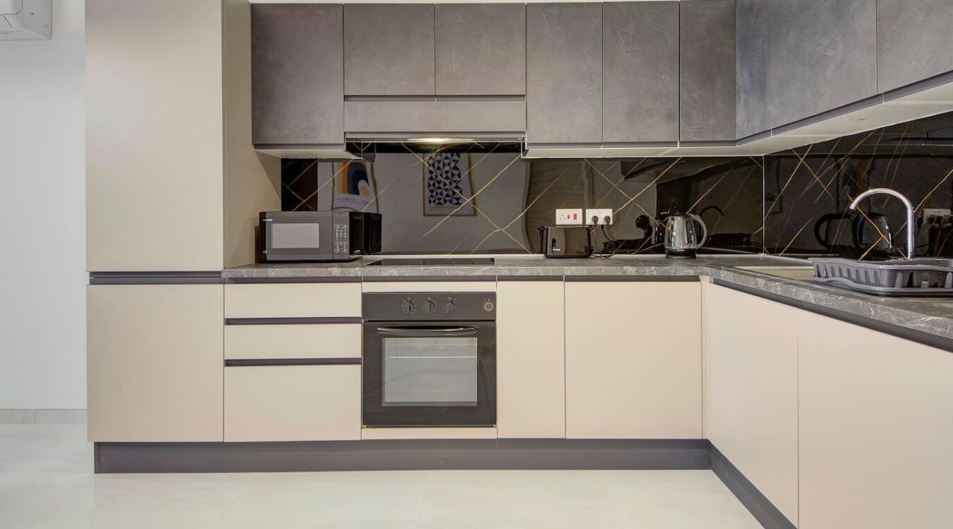 A modern kitchen with a built-in oven, microwave, and kettle.