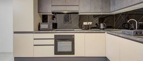 A modern kitchen with a built-in oven, microwave, and kettle.