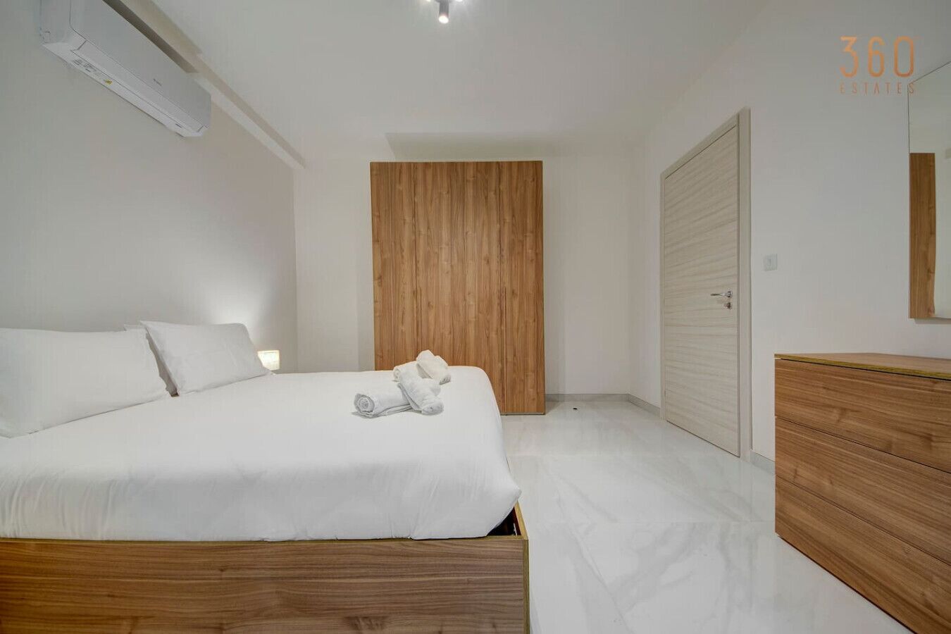 A modern bedroom with a wooden bed frame, a wooden wardrobe, and a white bedside table.