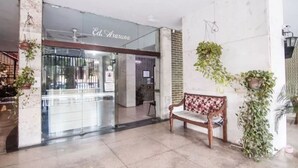 A lobby with a reception desk, a bench, and hanging plants. - SUH Flamengo 01 Praia Studio Dreams (Rio de Janeiro)