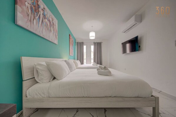 A modern hotel room with a large bed, a flat-screen TV, and artwork on the walls.