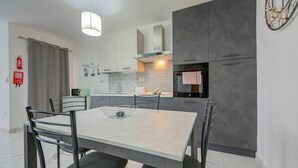 Una cocina moderna con una mesa de comedor, sillas y horno empotrado.