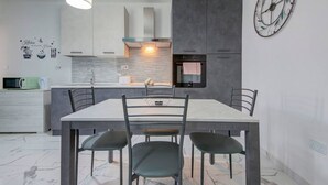 Una cocina moderna con una mesa de comedor y sillas, un microondas y un reloj en la pared.