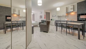 Una cocina moderna con suelo de mármol, un área de comedor con sofá gris y una mesa de comedor separada con sillas.