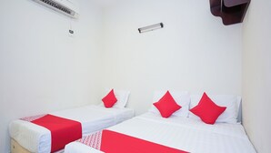 Dos camas individuales con ropa de cama roja y blanca, un aire acondicionado de pared y un pequeño estante marrón.