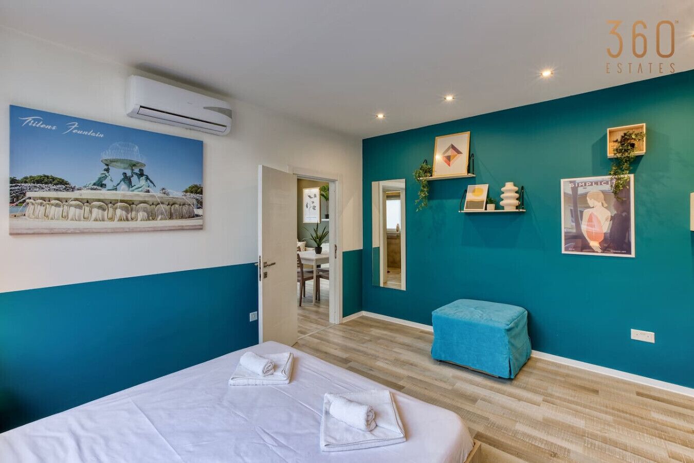 Una habitación de hotel con una cama, una pared azul, un espejo y un cartel.