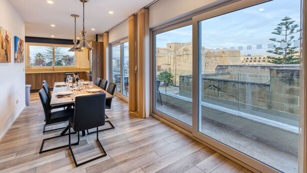 Un espace de restauration moderne, doté d’une grande table, de chaises et offrant une vue sur la ville grâce à de larges fenêtres.