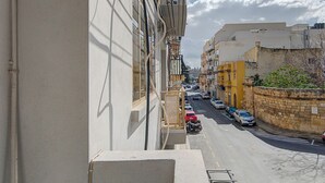 Una calle estrecha con coches estacionados y edificios a ambos lados.