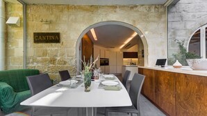 A dining area with a stone wall, a Cantina sign, a wooden bar, and a green sofa. - Stunning Villa with private pool & large terrace! (Balzan)
