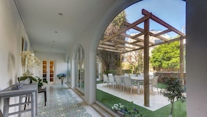 A covered patio with a pergola, a dining area with chairs and a table, and a view of a garden with a lawn and trees. - Stunning Villa with private pool & large terrace! (Balzan)