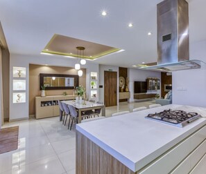 Uma cozinha moderna com ilha central, luminárias pendentes e fogão embutido.