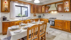 A spacious kitchen with wooden cabinets, a dining table set for four, and a large window providing natural light.