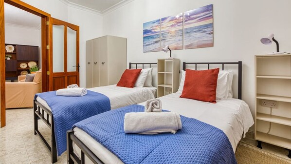 A hotel room with two beds, a wardrobe, a desk, and a shelf. - Comfortable 3BR Maisonette with PRVT Backyard & AC (San Ġwann)