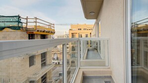 A balcony with a glass railing overlooking a cityscape.