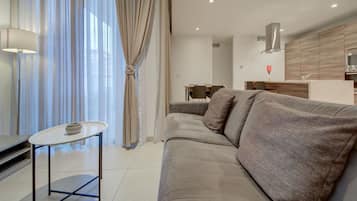 Un salon moderne avec un canapé, une petite table et un coin cuisine à l’arrière-plan.
