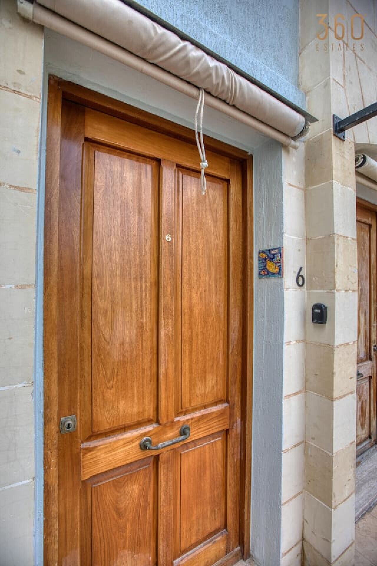 A wooden double door with a handle, a number '6' on the wall, and a small window above the door.