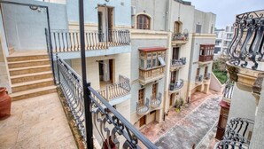 A multi-story residential building with balconies, a central courtyard, and a staircase leading to the upper floors. - Stylish St. Julian’s 1BR home, Cozy & Central! (St. Julian`s)
