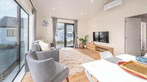 Ein modernes Wohnzimmer mit Sofa, Couchtisch, Fernseher und einem Essbereich mit Tisch und Stühlen.