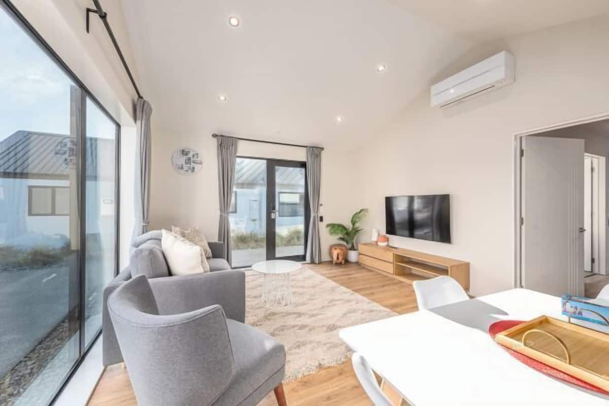 Un salon moderne comprenant un canapé, une table basse, un téléviseur et un coin repas avec une table et des chaises.