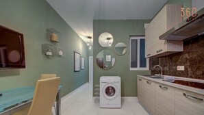 A modern kitchen with a built-in washing machine, a dining area with a table and chairs, and a large mirror on the wall. - Comfortable 1BR Apt with WIFI & AC in Gzira centre (Il-Gżira)