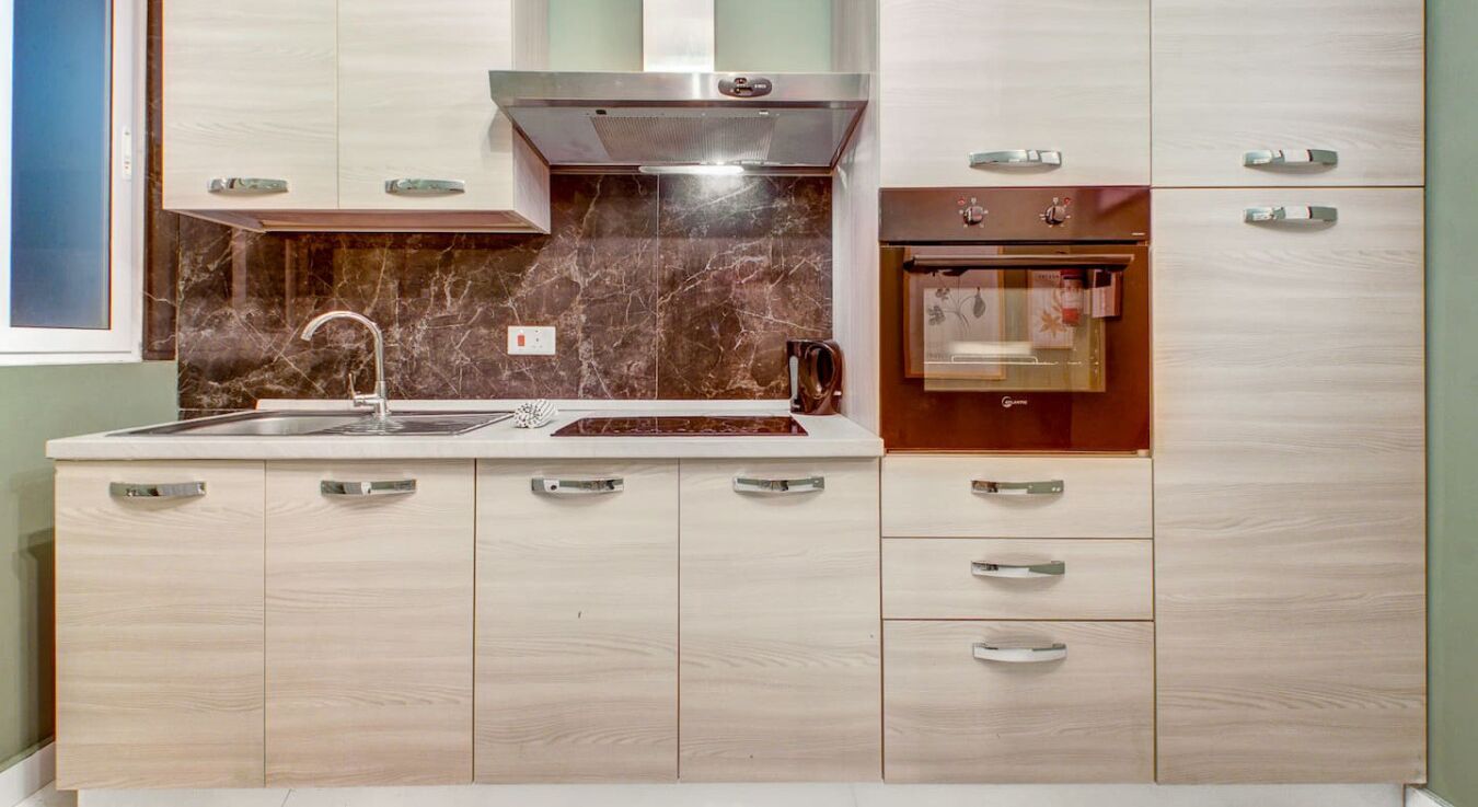 Una cocina moderna con un lavamanos de acero inoxidable, horno integrado y armarios de madera.