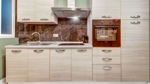 A modern kitchen with a stainless steel sink, a built-in oven, and wooden cabinets. - Comfortable 1BR Apt with WIFI & AC in Gzira centre (Il-Gżira)