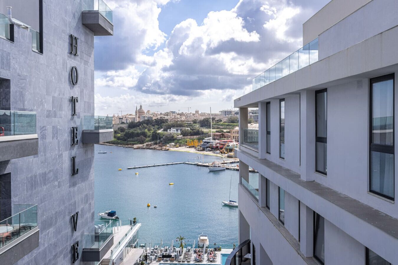 A high-rise hotel with a view of a marina and a cityscape in the background.